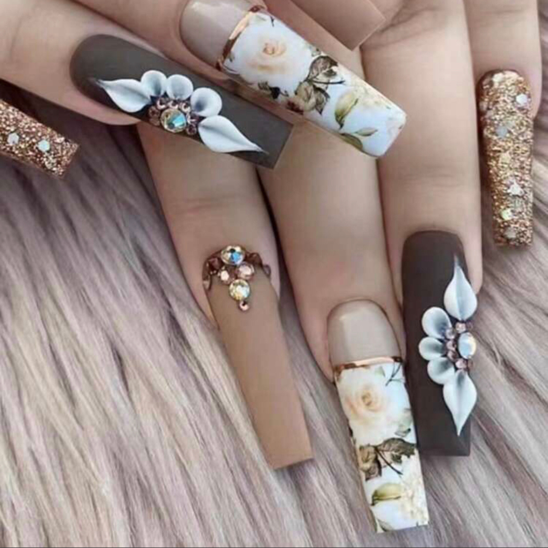 false press on nails that are brown and gold with flowers and gold foil designs in a long coffin shape