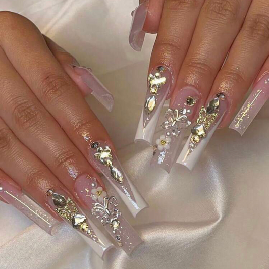 long press on nails that are shaped square and have big butterfly gems on the accent nails and a white ombre french tip effect on the other nails